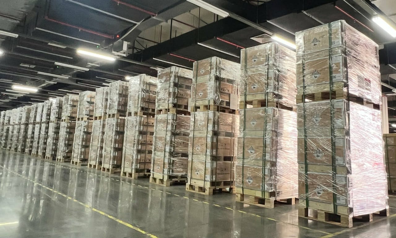 Allée de l'entrepôt de Saguenay, bordée de palettes de batteries Yilink filmées et cerclées